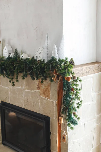 現代のクリスマスツリー 松のコーン 真鍮の鐘とリボンが付いている暖炉のマントルの枝 最小のスカンジナビアのリビングルームでスタイリッシュな装飾クリスマスの暖炉 — ストック写真