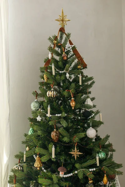 ヴィンテージゴールデンバブルとキャンドル付きのスタイリッシュな装飾クリスマスツリー 大気の冬の休日の準備 枝に掛かる現代のクリスマスの装飾 — ストック写真