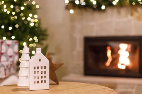 大气中的圣诞节时间 喜庆的房间里装饰着时尚的白色房子和树木 圣诞前夕 圣诞节的现代装饰放在桌上 以防止燃烧的壁炉 — 图库照片