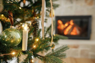 Mutlu Noeller! Noel süsleri ve ağaçta yanan şömineye yakın duran mumlar. Klasik takılar ve kurdelelerle süslenmiş güzel bir Noel ağacı. Noel arkaplanı
