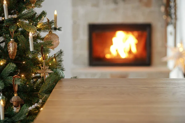 圣诞佳节的模板和木制板子都是模仿产品的 别致的木制桌子靠在有灯光和燃烧壁炉的圣诞树上 圣诞背景 复制空间 — 图库照片