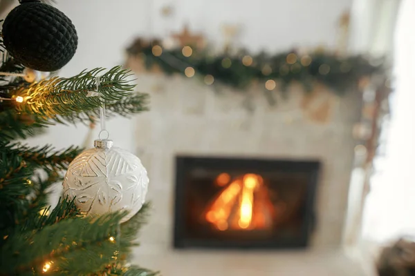 圣诞快乐 花哨的圣诞灯笼罩着树木 紧靠着燃烧的壁炉 装饰精美的圣诞树 有古色古香的灌木 彩灯和彩带 圣诞气氛 — 图库照片