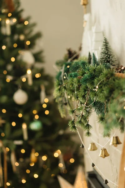 Stylowy Kominek Ozdobiony Bożonarodzeniowymi Gałęziami Girlandą Dzwonków Ozdobami Tle Choinkowych — Zdjęcie stockowe