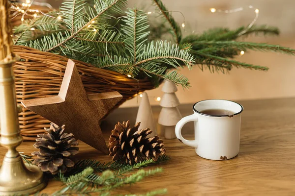 一杯别致的热茶 篮子里的冷杉枝条 木树和星星 松果和桌上的灯 现代圣诞乡村音乐生态友好装饰和杯子的模型 — 图库照片