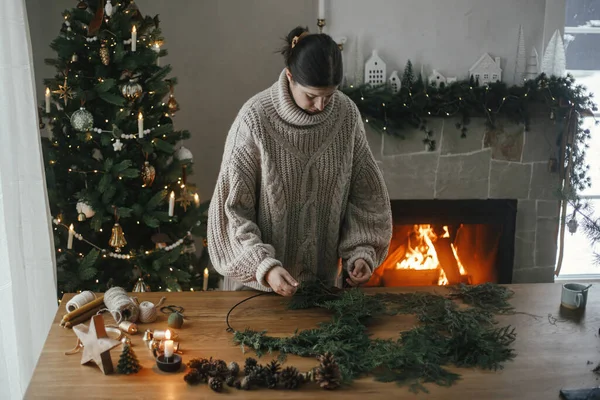 让圣诞乡村花环 女人用香柏木树枝 铃铛在木桌上做花环 寒假准备工作 — 图库照片