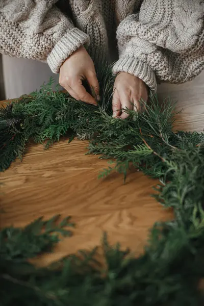 Zamykam Świąteczny Wieniec Ręce Trzymające Gałązki Cedrowe Tworzące Wieniec Drewnianym — Zdjęcie stockowe
