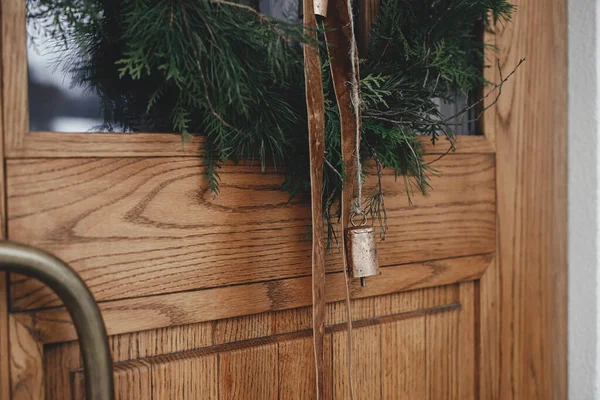 别致的圣诞花环 上面挂着老式的铃铛和带 挂在木门上 关门了 现代农舍入口装饰为寒假 圣诞快乐 节日快乐 — 图库照片