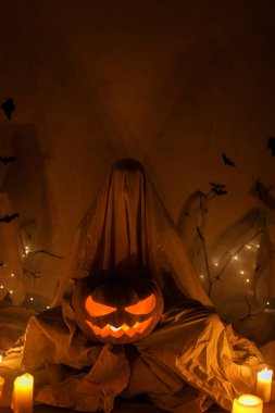 Örümcek ağının, örümceklerin, yarasaların ve mum ışıklarının arka planında parlayan Jack o fener kabağı tutan ürkütücü hayalet. Şeker mi şaka mı? İnsan hayalet gibi giyinir. Mutlu Cadılar Bayramı!