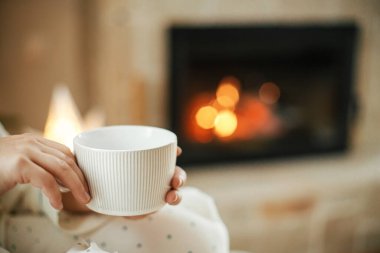 Sıcak Noel arifesi. Yanan şöminenin arka planında sıcak bir fincan çay ve şenlikli oturma odasında parlayan bir noel yıldızı. Mutlu Noeller ve mutlu Noeller.!