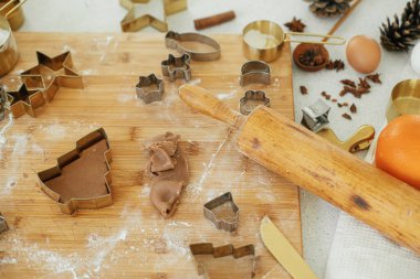 Zencefilli kurabiye yapıyorum. Ahşap tahtanın üzerinde altın işlemeli zencefilli ekmek hamuru un, baharat pişirme, modern beyaz mutfakta şenlikli süslemeler