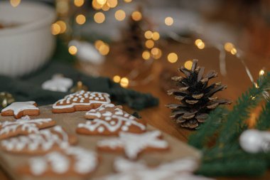 Kırsal ahşap masa üzerinde kremalı zencefilli kurabiyeler ve noel için altın ışıklar. Atmosferik Noel gelenekleri, aile zamanı. Kurabiyeleri şekerli süslemek