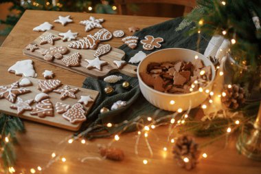 Mutlu Noeller! Tahta masa üzerindeki kremalı zencefilli kurabiyeler, köknar dalları, şenlikli dekorasyonlar, noel altın ışıkları. Atmosferik Noel arifesi, aile tatilleri