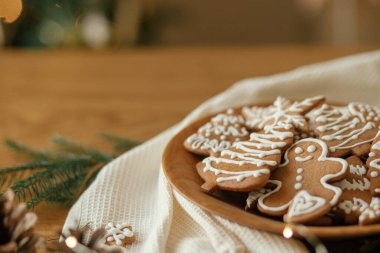 Mutlu Noeller! Köknar dalları ve şenlikli süslemeleri olan ahşap kırsal masa üzerinde kremalı zencefilli kurabiye. Atmosferik Noel tatili, aile zamanı