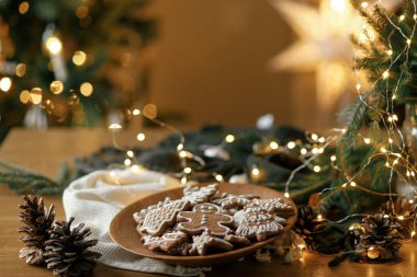 Mutlu Noeller! Ahşap masa üzerinde kremalı zencefilli kurabiyeler köknar dalları ve şenlikli süslemelerle yatıyordu. Atmosferik Noel gelenekleri, aile zamanı