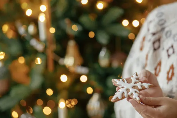 メリークリスマス クリスマスツリーゴールデンライトの背景にアイシングとジンジャーブレッドスタークッキーを保持している手 大気のクリスマス休日 家族の時間 — ストック写真