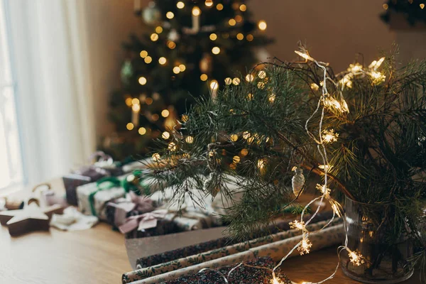 Stylowe Bożonarodzeniowe Złote Lampki Gałązkach Jodły Tle Stołu Świątecznymi Prezentami — Zdjęcie stockowe