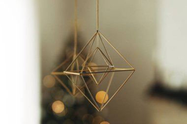 Evi Noel saman örümcekleriyle süslemek. Modern çiftlik evindeki şenlikli altın ışıkların arka planında asılı olan kırsal İskandinav saman süslemesi. Tatil gelenekleri.