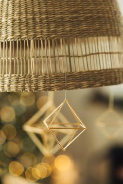 Modern çiftlik evindeki şenlikli altın ışıkların arka planında asılı duran İskandinav saman süslemesi. Evi Noel saman örümcekleriyle süslemek. Tatil gelenekleri.