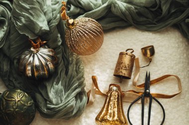 Mutlu Noeller! Şık Noel hediyeleri, kurdeleler, pirinç çanlar ve makas, rahat beyaz koltukta. Noel süslemeleri estetik düzlemdedir. Noel tatili için dekorasyon.