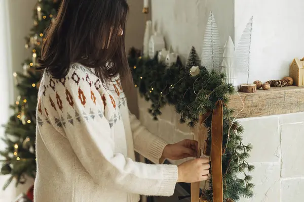 用天鹅绒缎带和老铃铛装饰在枞树枝上的圣诞壁炉 在现代农舍 穿着舒适毛衣的女人在壁炉架上挂着时尚的装饰 大气寒假 — 图库照片