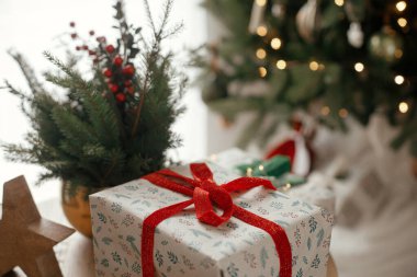 Mutlu Noeller ve mutlu Noeller! Şık bir Noel hediyesi, ahşap yıldız ve köknar dalları şenlikli İskandinav odasında altın ışığa karşı. Atmosferik resim