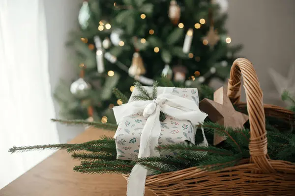 圣诞快乐 节日快乐 在丑闻的鸟类房间里 用时髦的包装着的圣诞礼物 带有冷杉枝条的乡村篮子和木制桌子上的现代装饰品与节日装饰树相映成趣 — 图库照片