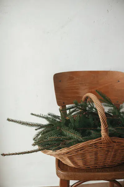 Stilvoller Rustikaler Korb Mit Tannenzweigen Auf Holzstuhl Gegen Ländliche Wand — Stockfoto