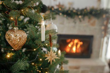 Mutlu Noeller! Noel süsleri ağaçta, yanan şömineye yakın duruyor. Güzel dekore edilmiş yılbaşı ağacı. Klasik mücevherleri, ışıkları ve kurdeleleri var. Noel atmosferi.