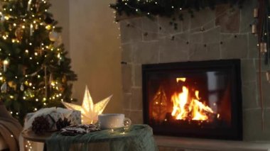 Mutlu Noeller! Şık bir hediye, zencefilli kurabiye ve çay fincanı Noel ışıklarına ve yanan şömineye karşı. Sıcak Noel arifesi. Kış kızlık zarı görüntüleri