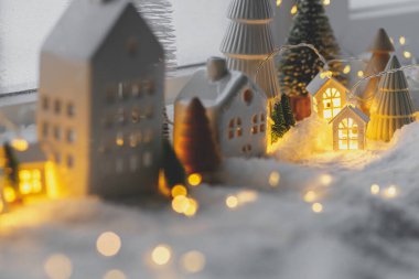 Sıcak Noel minyatür köyü. Şık küçük seramik evler ve yumuşak kar örtüsü üzerinde ağaçlar ve akşamları parlayan ışıklar. Atmosferik kış köyü hala canlıdır. Mutlu Noeller.!
