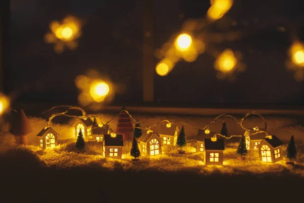 大気のミニチュアウィンター村 スタイリッシュでかわいい小さな輝く家やクリスマスツリーは 夜の部屋で金色のライトボケと柔らかい雪の毛布に クリスマスの背景 ハッピー ホリデー — ストック写真