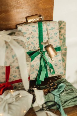 Mutlu Noeller ve mutlu tatiller! Şık Noel hediyeleri, eski ahşap koltukta şeritlerle süslenmiş şenlikli kağıt, makas, kozalak ve ışıklar. Çevre dostu hediyeler. Kapatın.