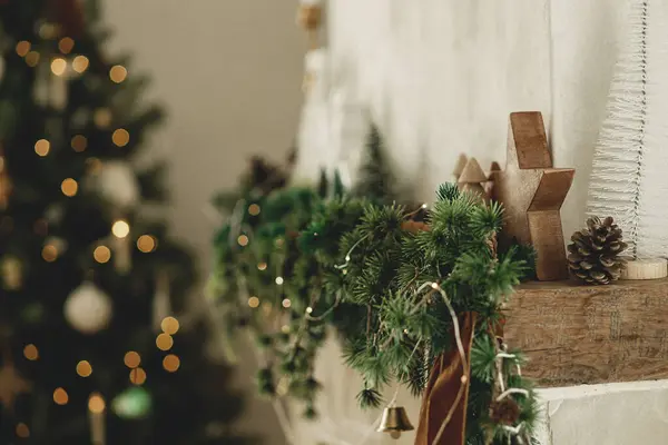 时尚的圣诞木星 云杉枝 壁炉壁炉架上的铃铛 紧靠着圣诞树灯的背景 现代农舍客厅装饰的节日乡村壁炉 — 图库照片