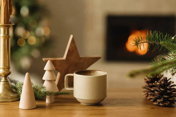 コージーウィンター 暖かいお茶のスタイリッシュなカップ 火の枝 木の木 火の暖炉に対するテーブルの上の松のコーン 現代クリスマス素朴なエコフレンドリーな装飾 スカンジナビアの衛生 — ストック写真