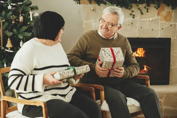 Mutlu son sınıf aileleri Noel hediyelerini değiş tokuş ediyor ve şık, şenlikli oturma odasında sıcak şöminenin keyfini çıkarıyor. Güzel yaşlı bir çift ellerinde hediyelerle oturuyor. Mutlu Noeller.!