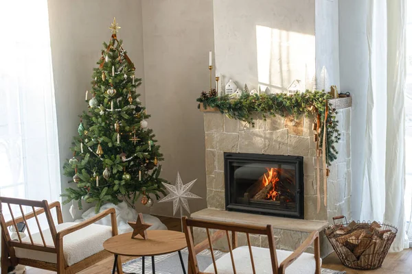 Stylish christmas living room with modern decorated christmas tree with vintage baubles and scandinavian decor on fireplace mantel with bells and ribbon. Atmospheric christmas eve in farmhouse
