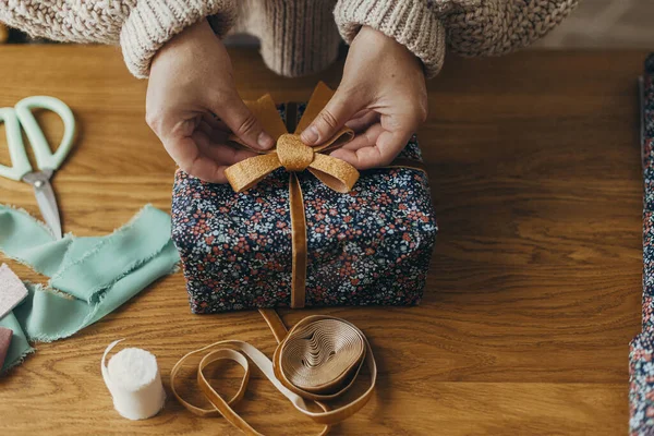 Wrapping christmas gifts. Hands in cozy sweater wrapping stylish