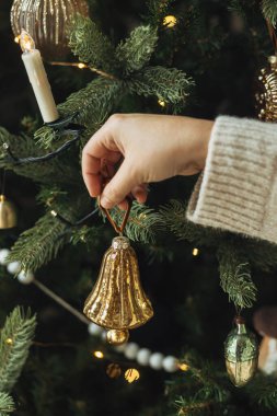 Noel ağacını şık takılarla süslemek. Eller rahat süveter içinde ağaç dalına asılmış eski püskü süsler. Atmosferik kış tatili geleneği, aile zamanı
