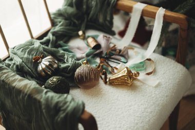 Mutlu Noeller! Şık Noel hediyeleri, kurdeleler, pirinç çanlar ve makas, rahat beyaz koltukta. Noel süsleri estetik. Noel tatili konsepti için dekorasyon.