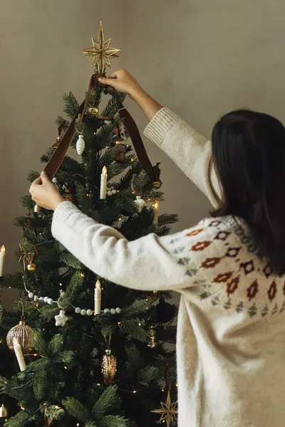 スタイリッシュな金星とリボンでクリスマスツリーを飾ります 木の枝にヴィンテージの装飾を掛けている居心地の良いセーターの女性が閉じます 大気の冬の休日の伝統 家族の時間 — ストック写真