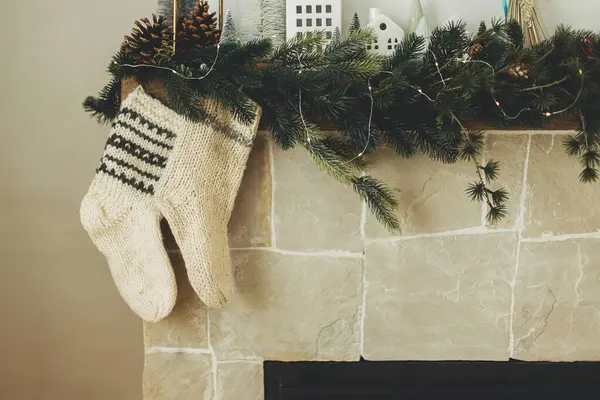 舒适的长袜挂在现代农舍客厅的壁炉架上 带有温暖针织长袜的乡村圣诞壁炉和冷杉枝条上的时尚装饰 大气寒假 — 图库照片