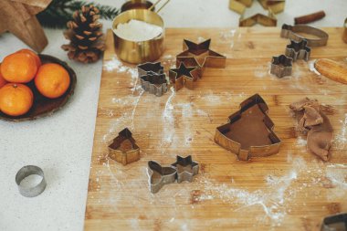 Ahşap tahtada altın işlemeli zencefilli hamur hamuru un, baharat pişirme, modern beyaz mutfakta şenlikli süslemeler. Noel kurabiyesi yapıyorum.