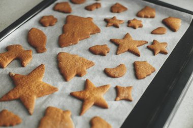 Yeni pişmiş zencefilli kurabiyeler, modern beyaz mutfaktaki pişirme tepsisinde Noel şenliği şekillerinde. Noel kurabiyesi yapıyorum.