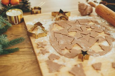 Altın kesicili zencefilli hamur, merdane, baharat pişirme ve sade ahşap masa süsleri. Noel kurabiyesi yapmak, atmosferik tatil zamanı.