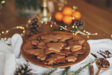 Köknar dalları, kozalak ve peçeteli tahta tabakta Noel kurabiyesi. Mutlu Noeller! Lezzetli taze zencefilli kurabiyeler yakın çekim atmosferik tatil