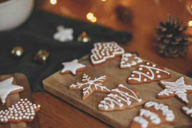Kırsal ahşap masa üzerinde kremalı zencefilli kurabiyeler ve noel için altın ışıklar. Atmosferik Noel gelenekleri, aile zamanı. Kurabiyeleri şekerli süslemek