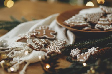 Noel zencefilli kurabiyeler, süslü sade masa kremalı süslemeler, köknar dalları, altın aydınlatma. Mutlu Noeller! Lezzetli zencefilli kurabiyeler, atmosferik zaman