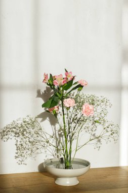 Kırsal arka planda kasede güzel pembe ve beyaz çiçekler. Kenzan 'da narin çiçek kompozisyonu ya da güneş ışığında çiçek tokası. Modern çiçek aranjmanı