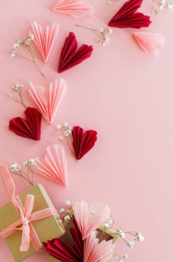Sevgililer günü yatıyordu. Pembe ve kırmızı kalpler, çiçekler ve pembe arka planda hediye kutusu. Sevgililer Günün kutlu olsun! El işi kutusundan modern kalp kâğıdı kesimleri. Aşk ve Anneler Günü