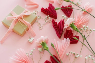 Sevgililer Günün kutlu olsun! Zarif çiçekli, pembe ve kırmızı kalpler ve pembe arka planda duran kalp kolyesi. Sevgililer Günü kartları, kağıt kesikleri ve mücevherler. Aşk ve Anneler Günü